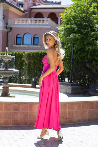 Woman in a pink dress standing in front of a fountain and building