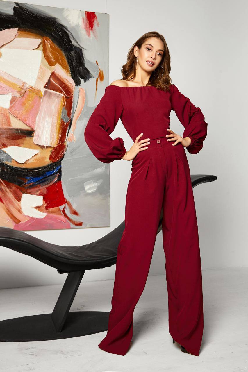 Woman in a red jumpsuit posing in front of a modern abstract painting.