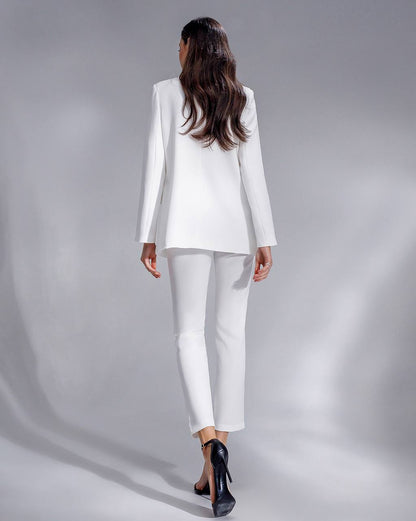 Woman wearing a white suit standing against a gray background