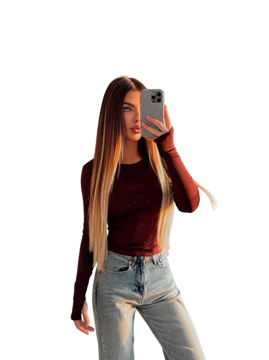 Woman taking a mirror selfie wearing a brown top and light blue jeans on a white background
