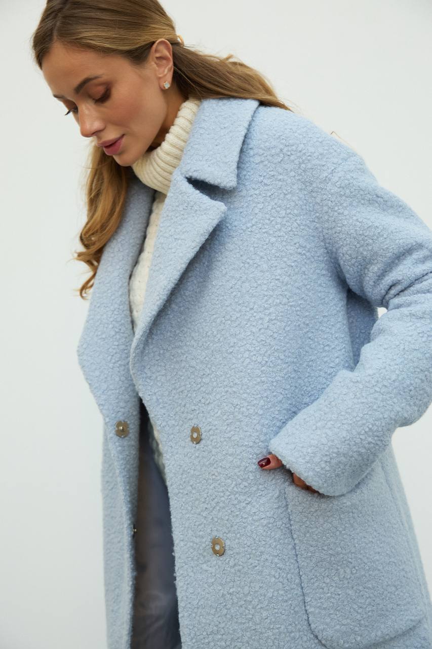 Woman wearing a light blue coat with a white background