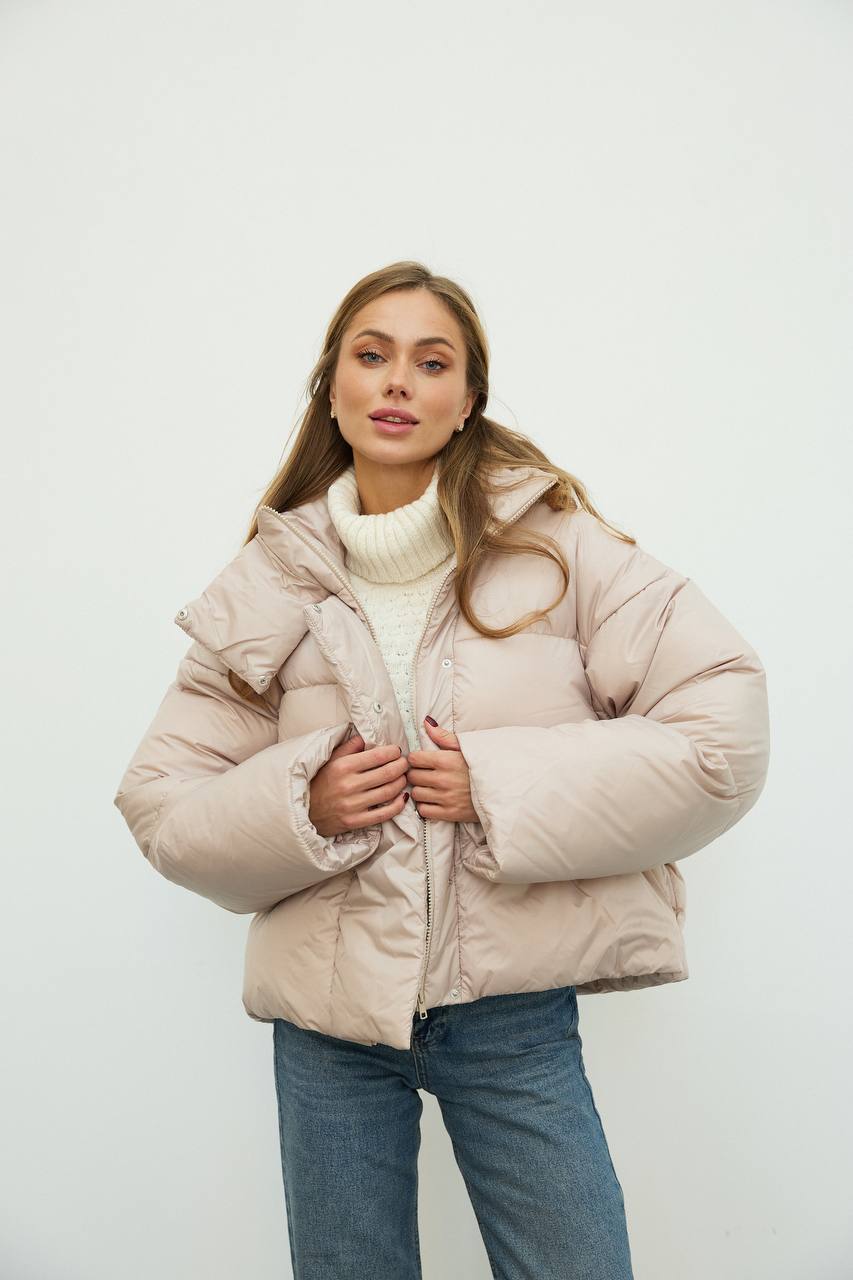 Woman wearing a beige puffer jacket on a white background