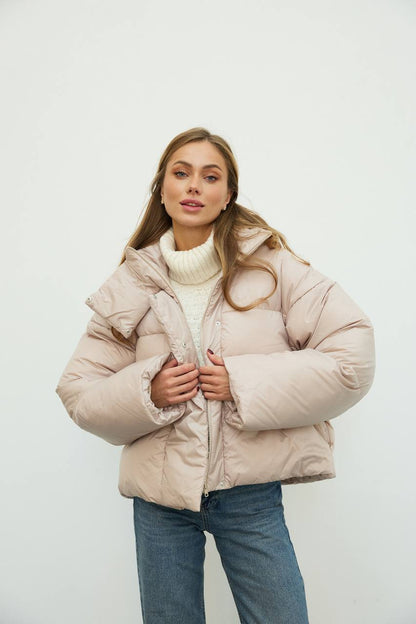 Woman wearing a beige puffer jacket on a white background
