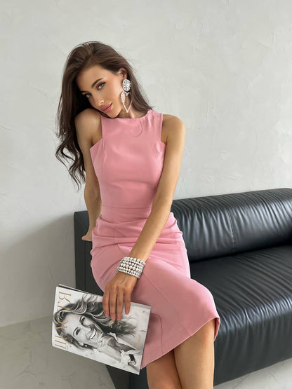 Woman in a pink dress holding a clutch with a black and white design, sitting on a black leather couch.