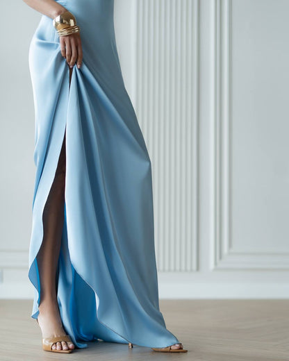 Woman wearing a light blue evening gown with a high slit in a minimalistic setting