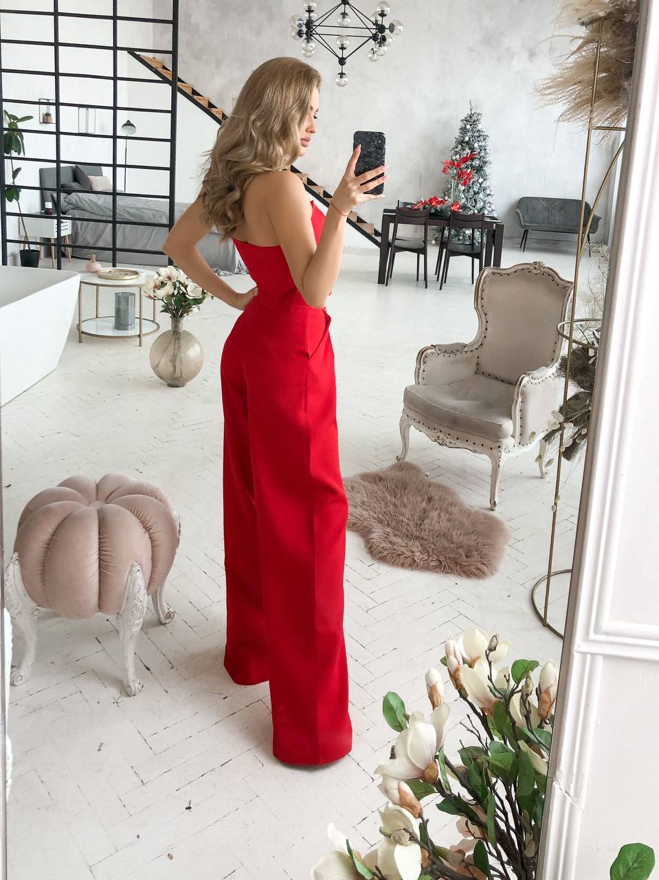 Woman in a red dress taking a mirror selfie in a stylish room with decor elements.