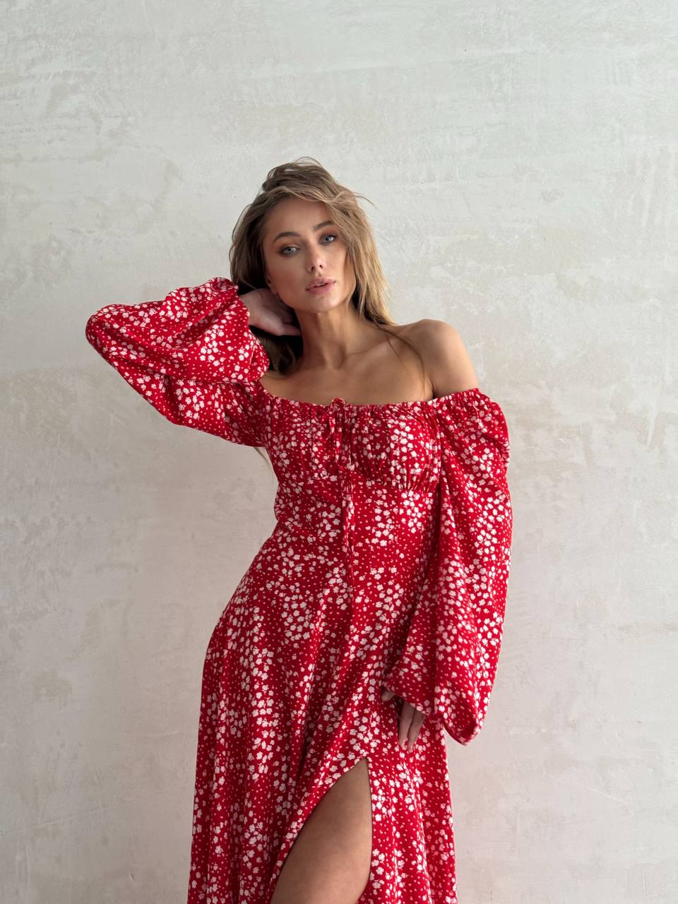 Woman wearing a red floral dress against a plain background