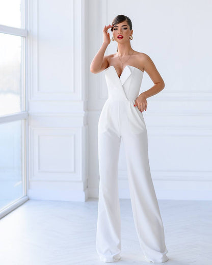 Woman wearing a white strapless jumpsuit in a bright room.