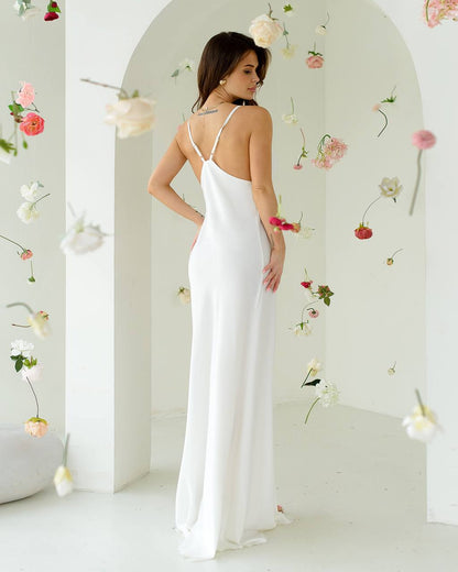 Woman in a white dress standing in a room with floral decorations.