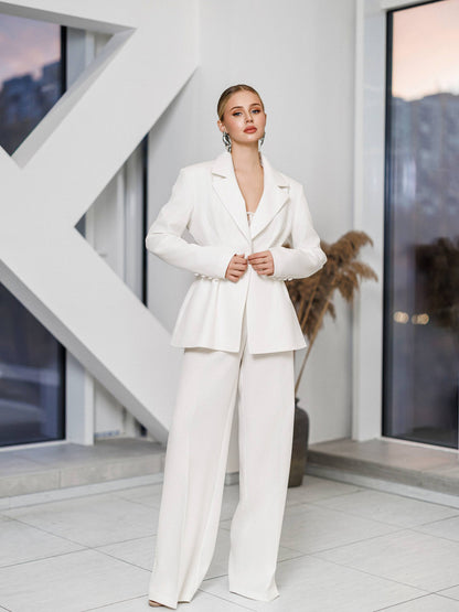 Woman in a white suit standing in a modern indoor setting