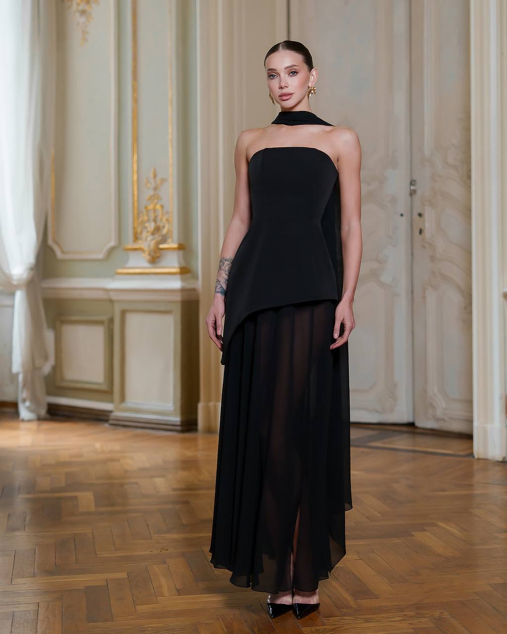 Woman wearing a black strapless dress in an elegant interior setting