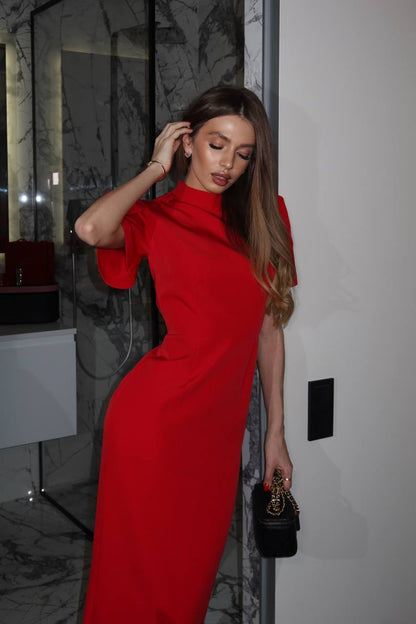 Woman in a red dress standing indoors with a neutral background