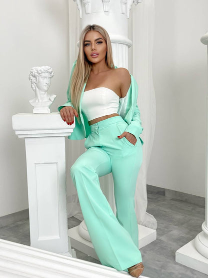 Woman in mint green outfit posing in a decorative room.