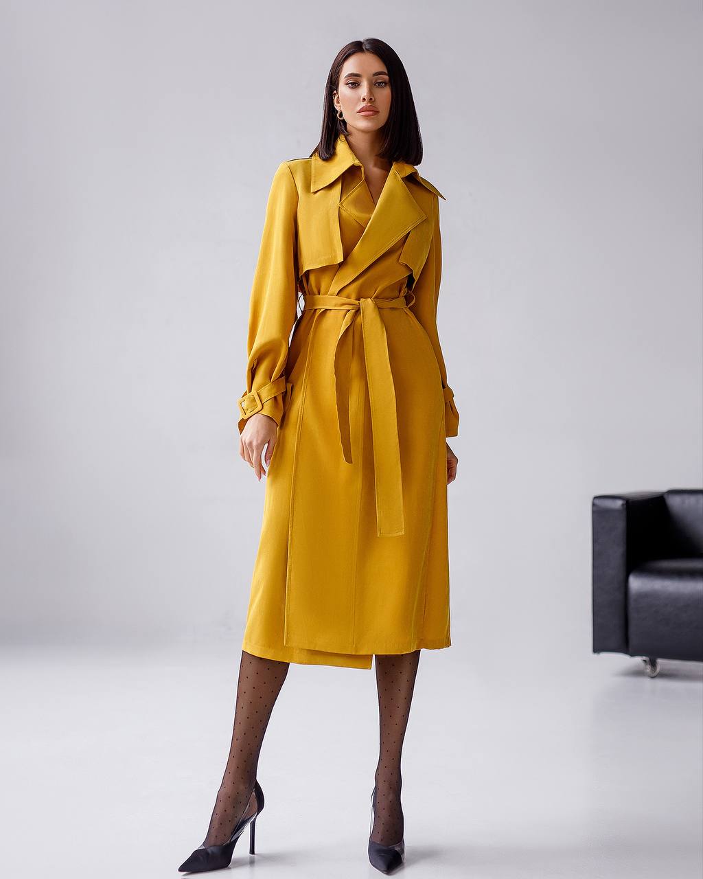 Woman wearing a yellow trench coat on a plain background