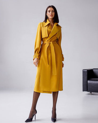 Woman wearing a yellow trench coat on a plain background