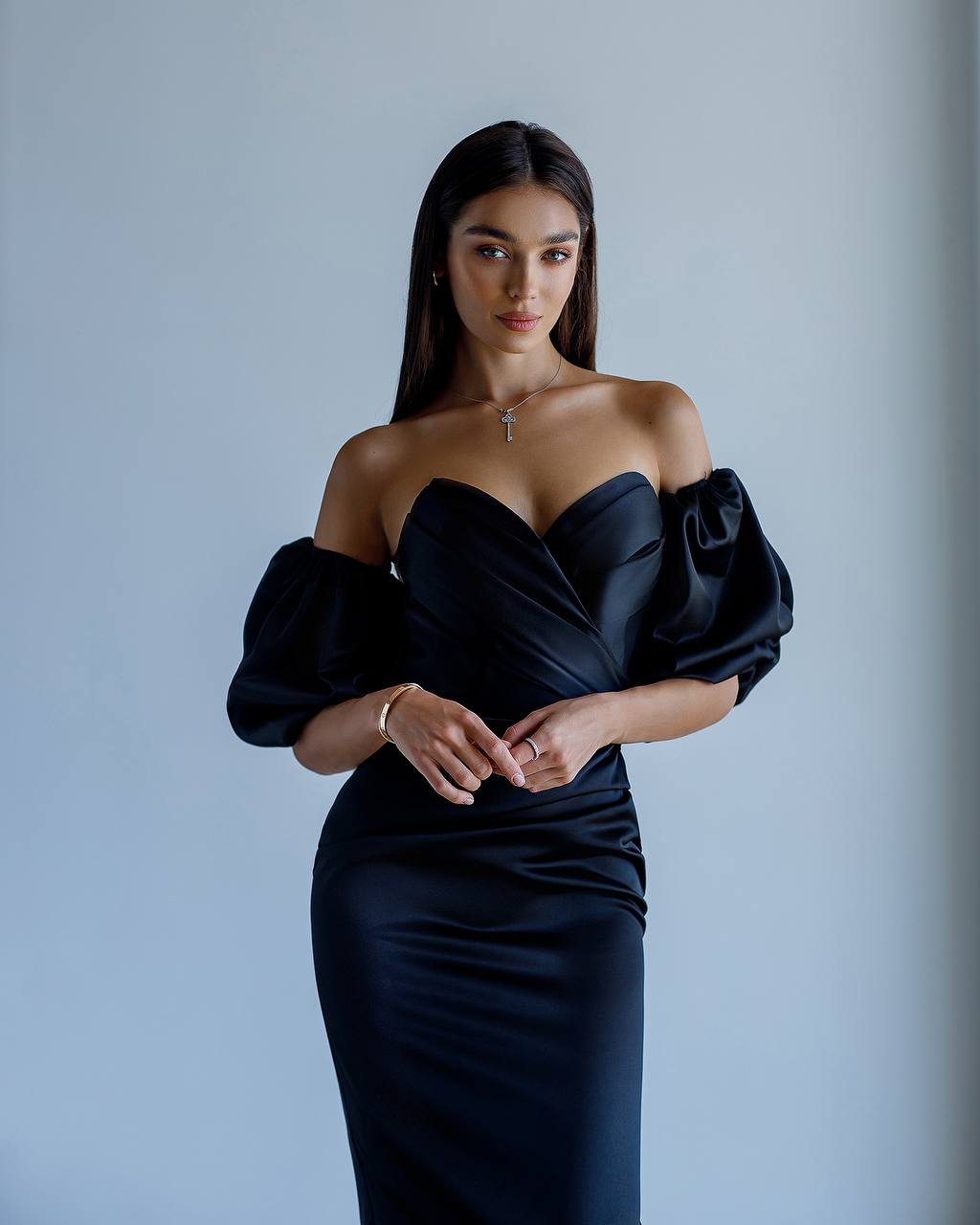 Woman wearing a black off-shoulder dress against a plain background