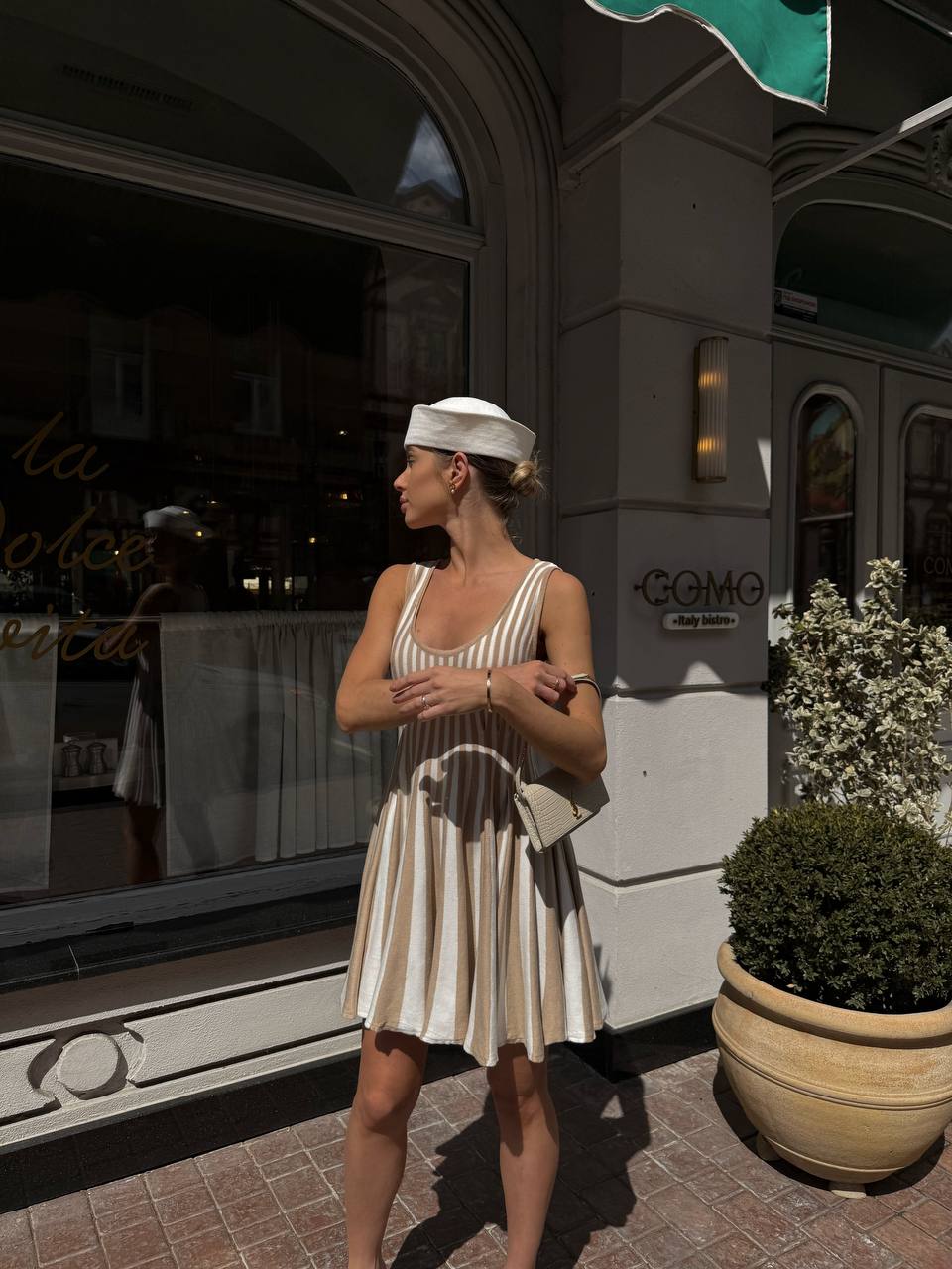 Woman in a striped dress standing outside a building with a sign that reads 'Congo'.