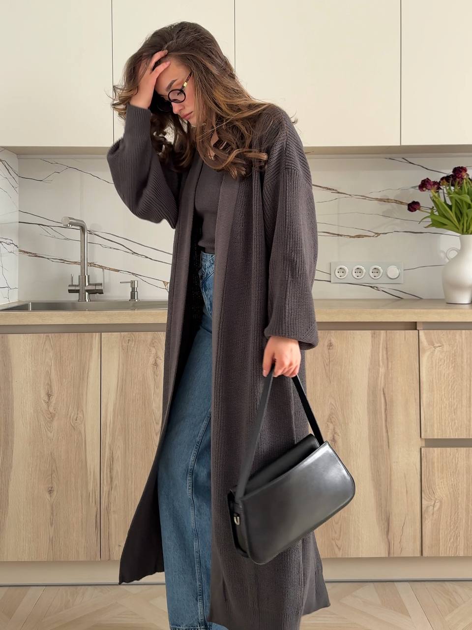 Woman in a kitchen holding a black handbag