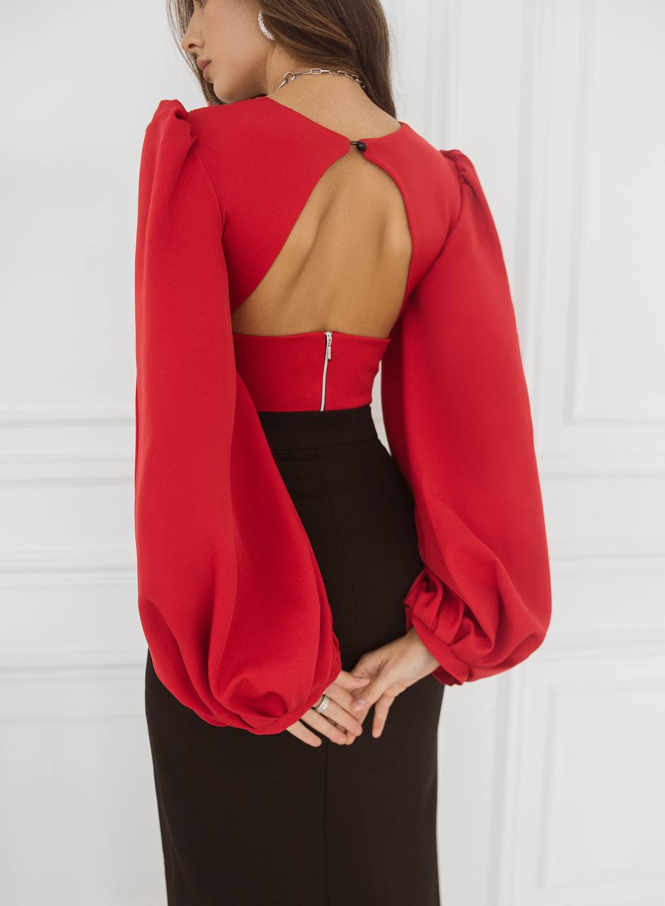 Red blouse with puffed sleeves and open back worn by a person against a white background