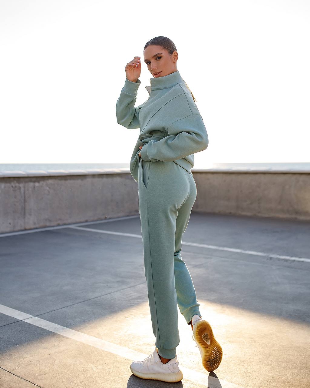 Person wearing a light blue tracksuit standing on a rooftop.