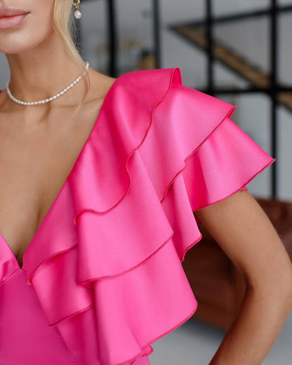 Close-up of a bright pink ruffled top worn by a person.