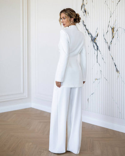 Woman in a white outfit standing in a room with marble wall.