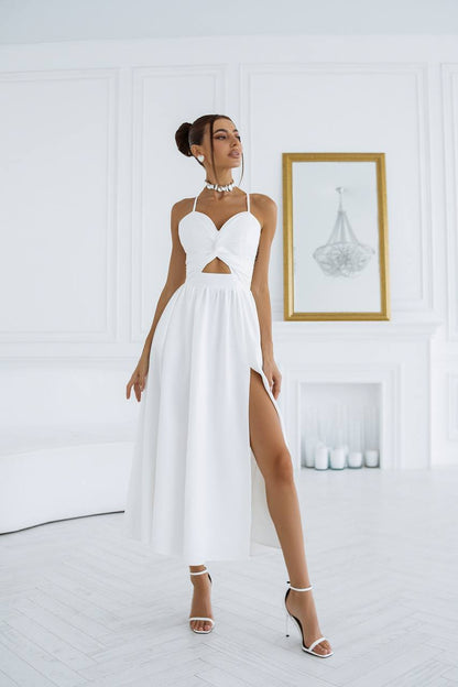Woman wearing a white dress with a high slit in a minimalistic room.