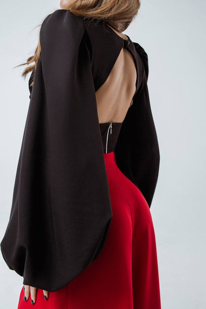 Black open-back top and red pants on a plain background