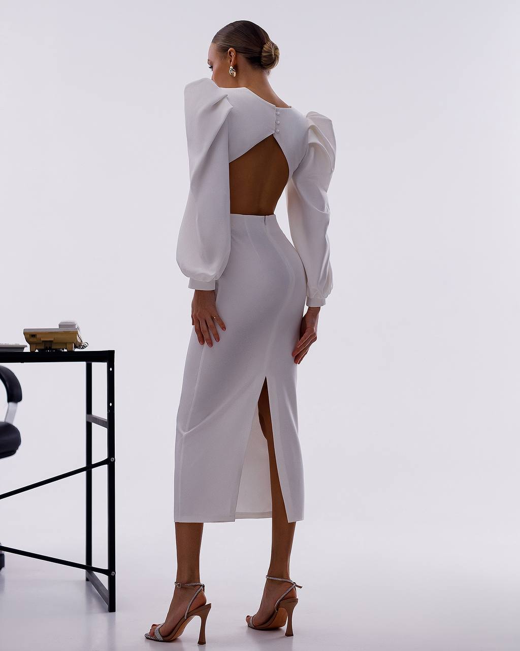 Person wearing a white outfit with cut-out design on a plain background