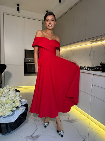 Woman in a red off-shoulder dress standing in a modern kitchen.