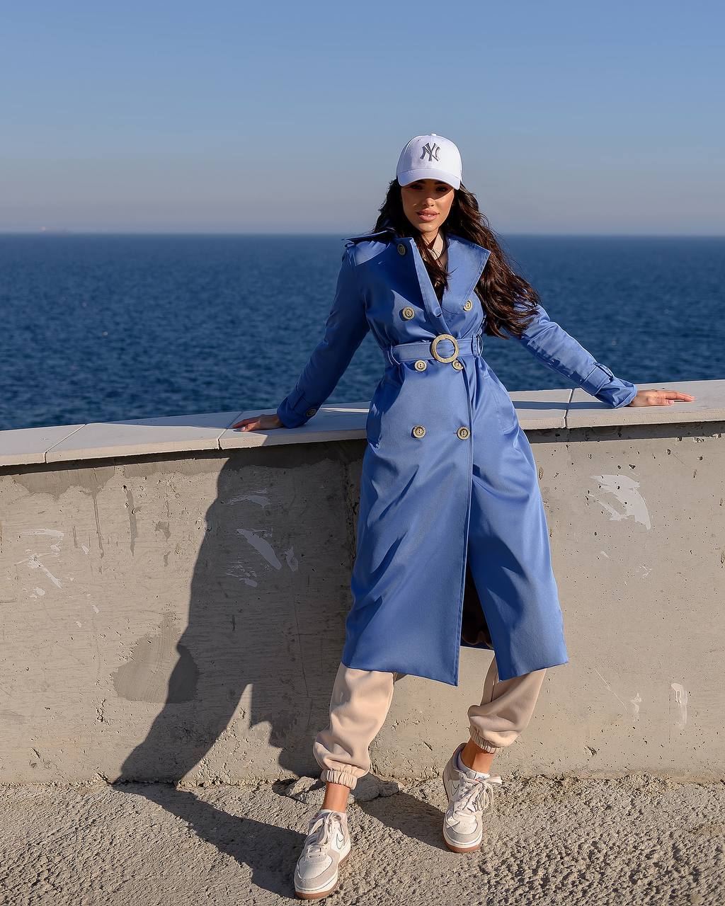 Person wearing a blue coat and white cap standing by the ocean