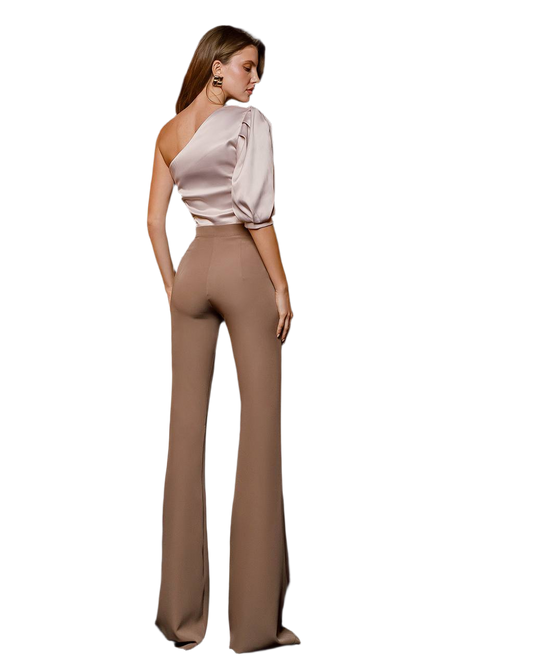 Woman wearing a one-shoulder top and high-waisted pants on a white background