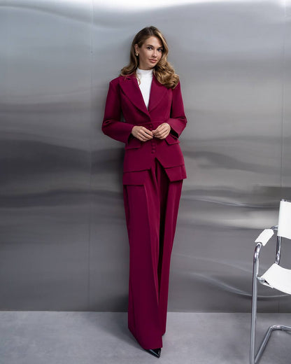 Woman wearing a magenta suit standing against a gray background