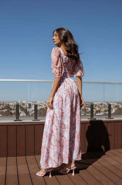 Woman in a floral dress standing on a rooftop with a clear blue sky