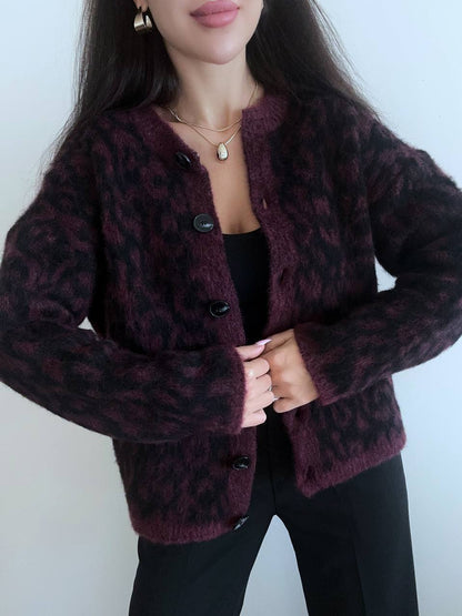 Person wearing a dark purple cardigan with a subtle pattern against a plain background