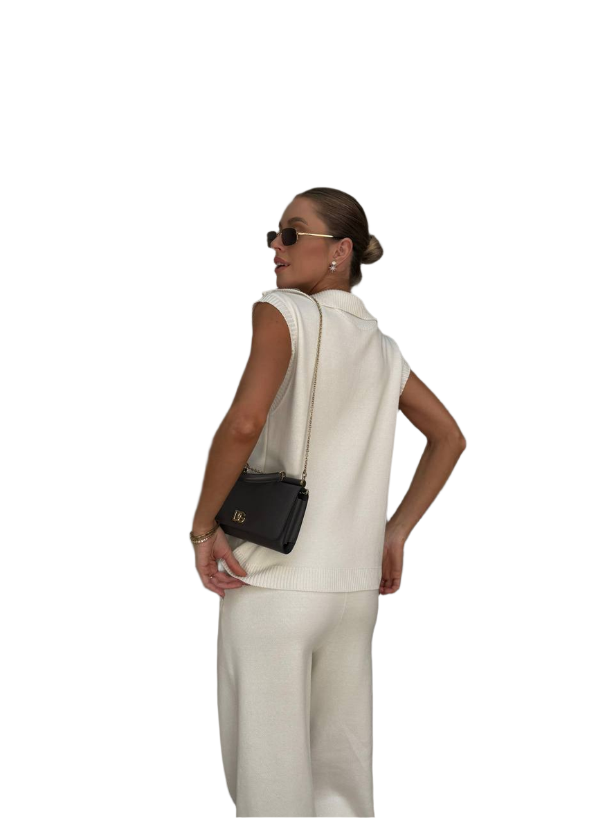 Woman in a white outfit with a black handbag on a white background