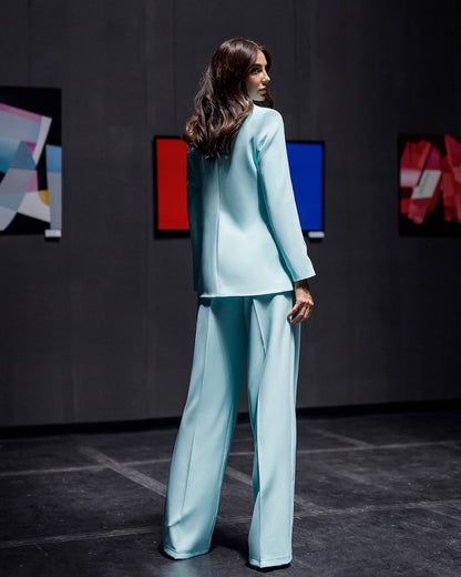 Woman in a light blue suit standing in a room with abstract art on the wall.