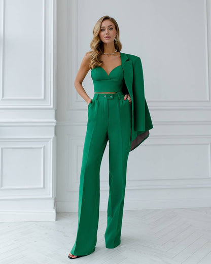 Woman wearing a green outfit with a jacket against a white wall
