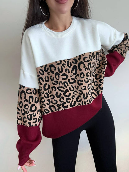 Person wearing a white sweater with leopard print and red sections on a plain background