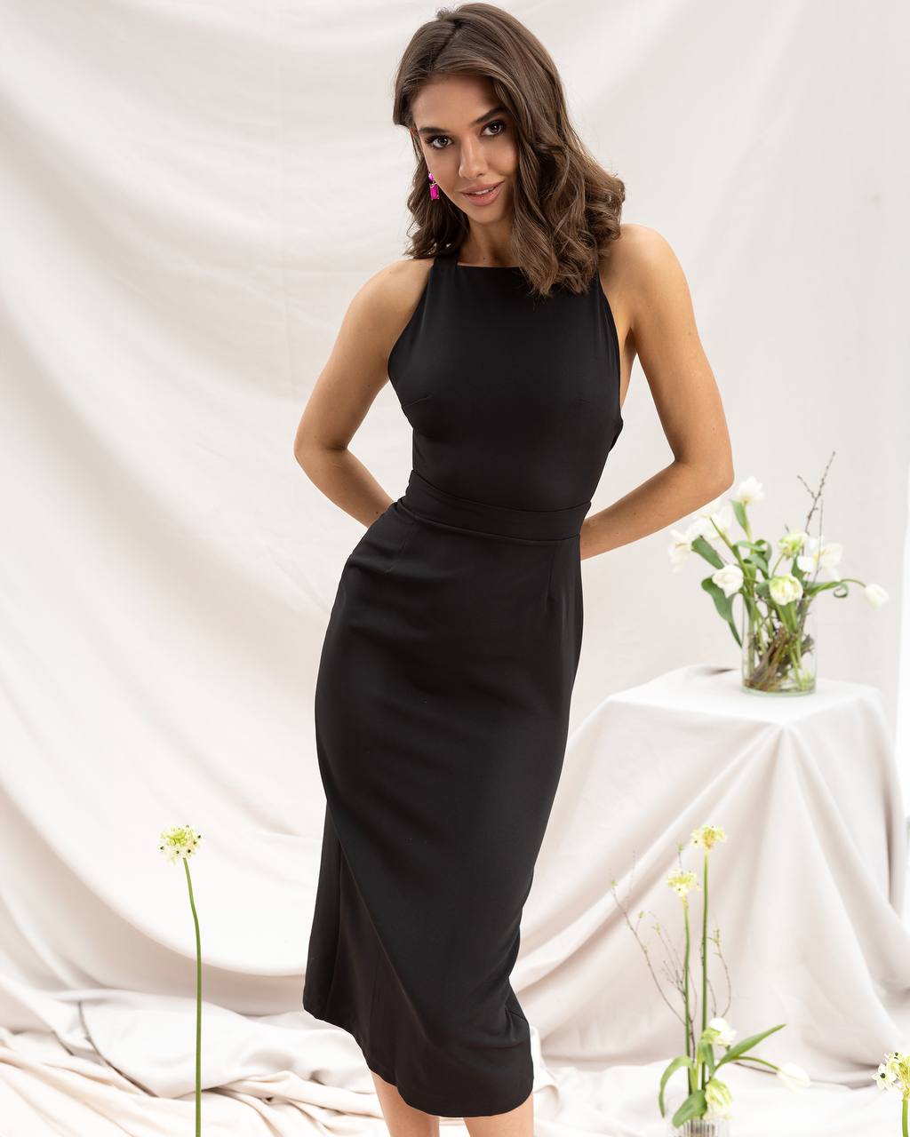 Woman wearing a black sleeveless dress against a white background