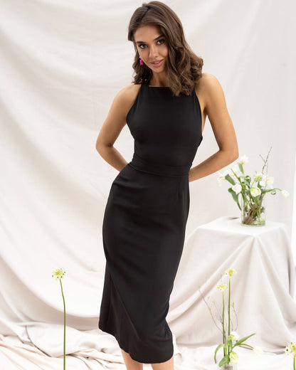 Woman wearing a black sleeveless dress against a white background