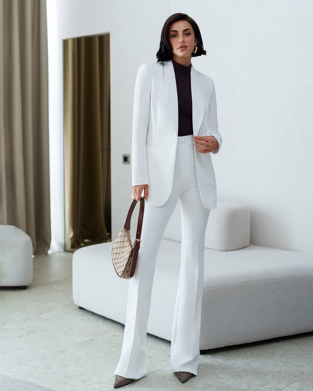 Woman in a white suit standing in a modern living room.