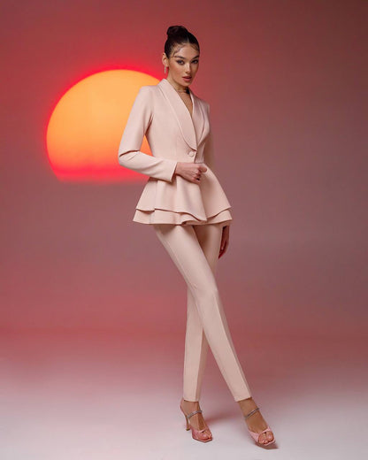 Woman in a pink suit standing against a gradient background with a sun-like shape.