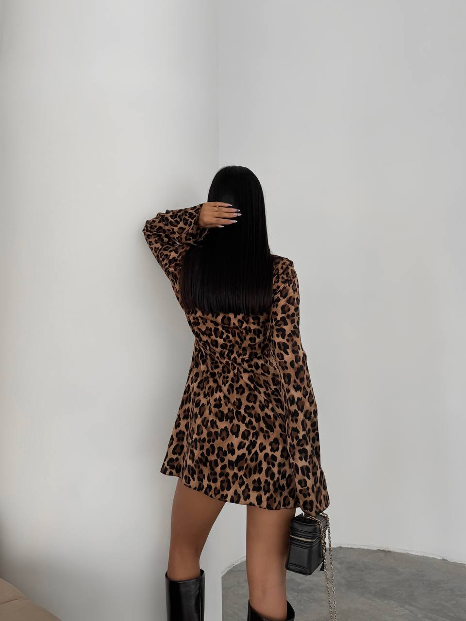 Person wearing a leopard print dress against a plain background