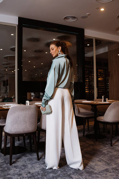 Woman standing in a modern restaurant with tables and chairs.