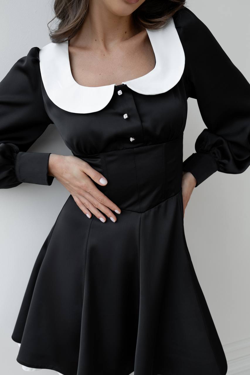 Black dress with white collar on a plain background