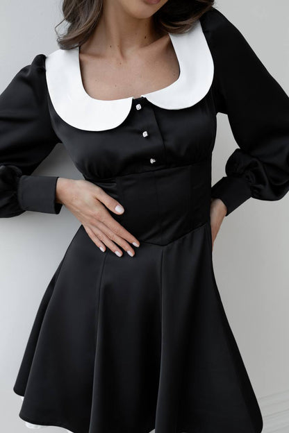 Black dress with white collar on a plain background