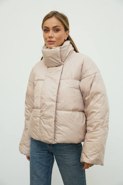 Woman wearing a beige puffer jacket against a white background