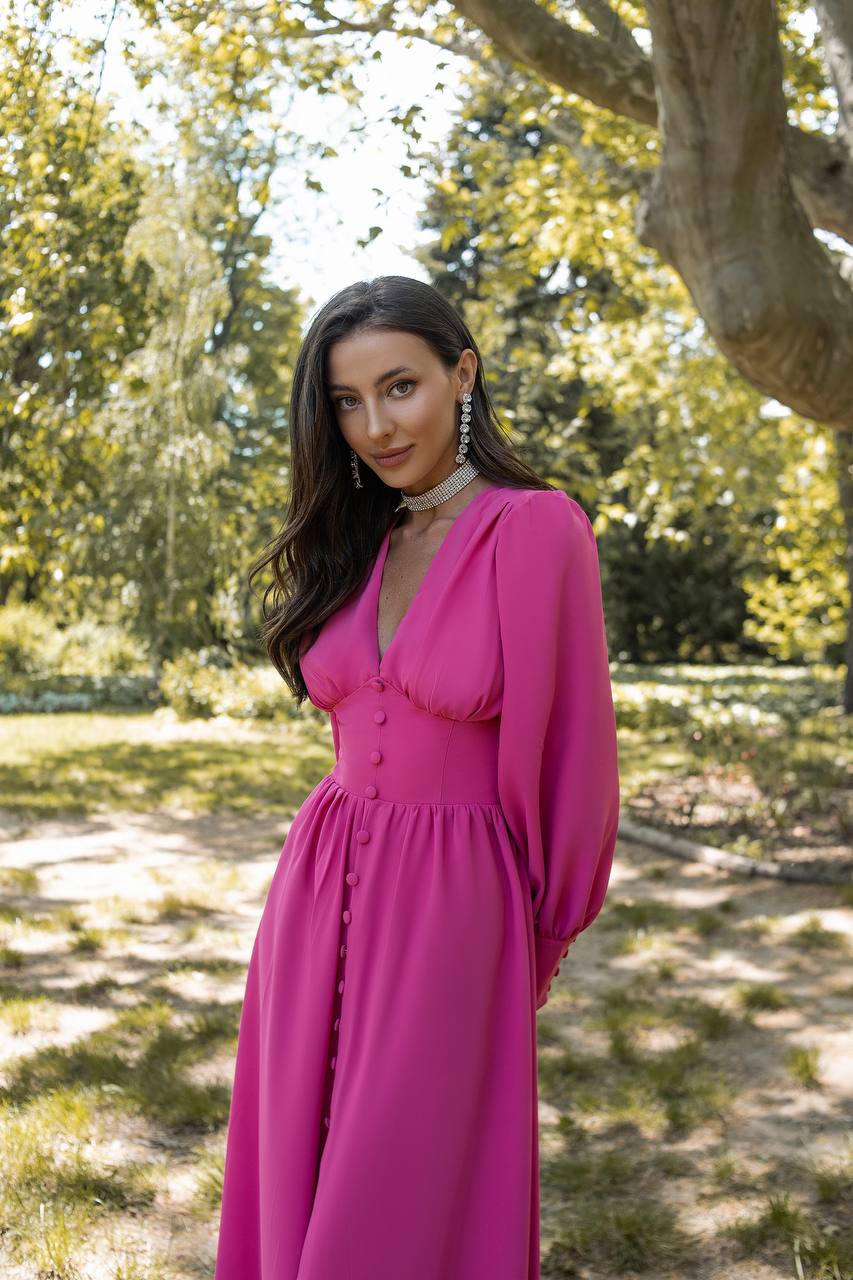 Woman in a pink dress standing in a park with trees in the background