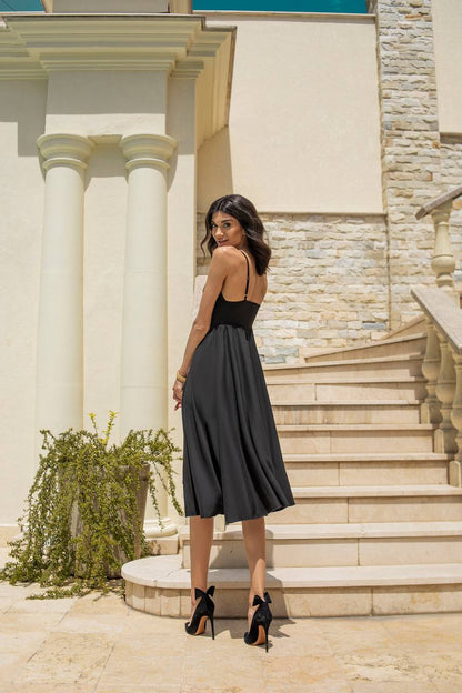 Woman in a black dress standing on stone steps with classical architecture in the background